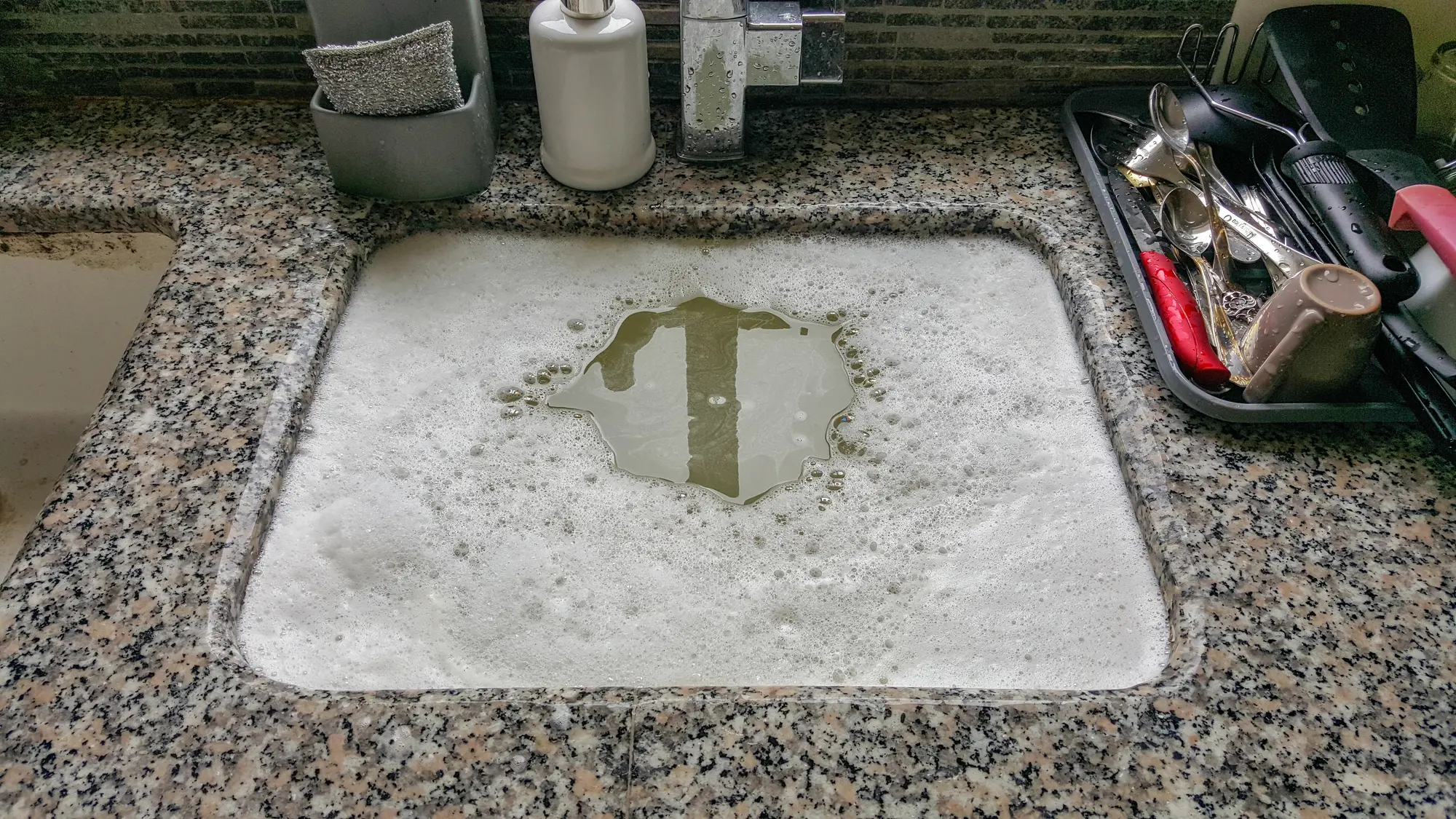 warmer-water-clogged-drain-simpsonville Clogged kitchen sink filled with soapy water not draining in a Simpsonville, SC home