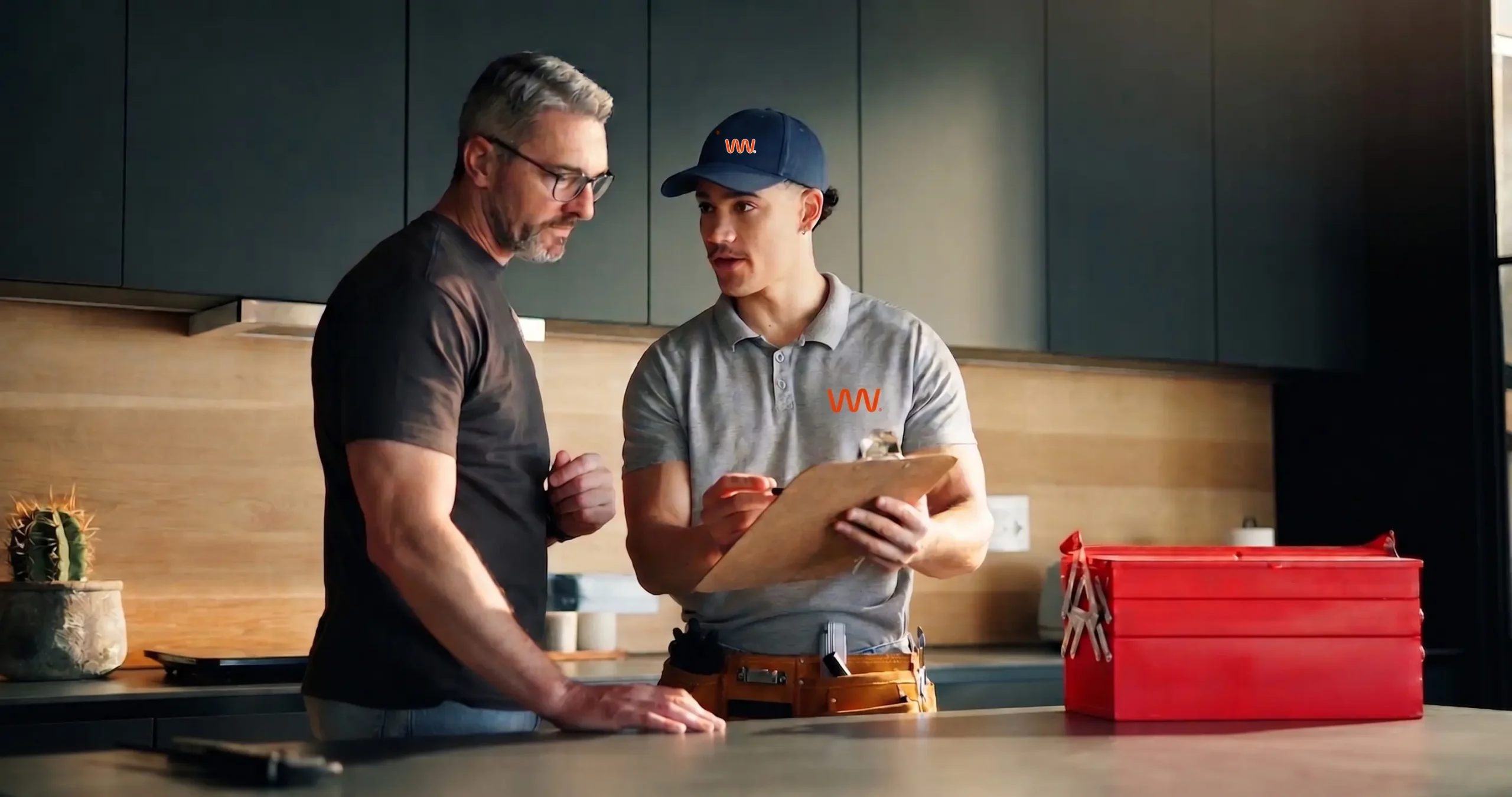Warmer Water plumber reviewing repair costs with a homeowner in the kitchen